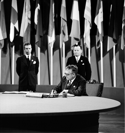 The Australian Minister for External Affairs and Attorney-General, Dr HV Evatt, signs the Charter of the United Nations on behalf of Australia, watched by the Australian Deputy Prime Minister, Francis M Forde (right), San Francisco, 26 June 1945