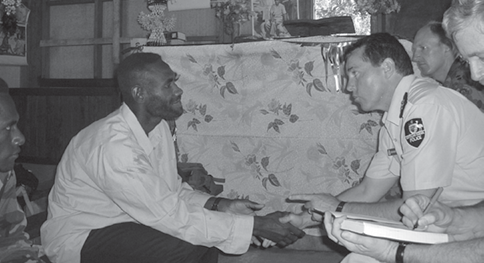 The Australian Federal Police Commander of the Regional Assistance Mission Solomon Islands (RAMSI) Participating Police Force, Assistant Commissioner Ben McDevitt (second right), negotiates with self-proclaimed warlord, head of the Guadalcanal Liberation Front, Harold Keke (left), accompanied by the RAMSI Special Coordinator, Nick Warner (right), and the RAMSI Taskforce Commander, Lieutenant Colonel John Frewen (third right), Nera Isuna, August 2003. [Australian Federal Police]