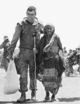 An Australian soldier serving as part of the UN's Unified Task Force (UNITAF) assists a Somali woman at a food distribution centre in the Bay Region, southern Somalia, March 1993. [Australian War Memorial/Gary Ramage]