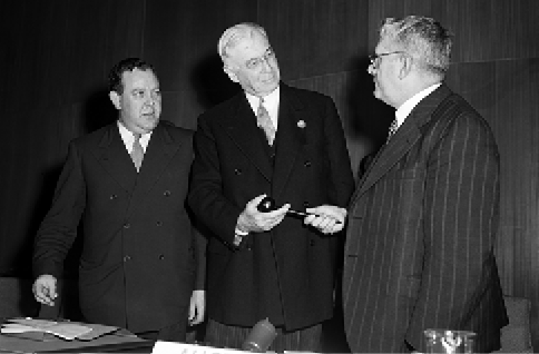The Australian Minister for External Affairs and Attorney-General, Dr Herbert V Evatt (right), receives the gavel from the US Representative and Temporary Chairman of the UN Atomic Energy Commission, Bernard M Baruch (centre), upon his designation as the first Chairman of the Commission. UN Secretary-General Trygve Lie looks on, New York, 14 June 1946. [UN Photo]