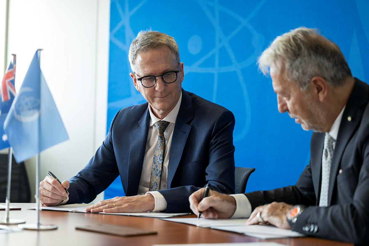 Two men signing documents.