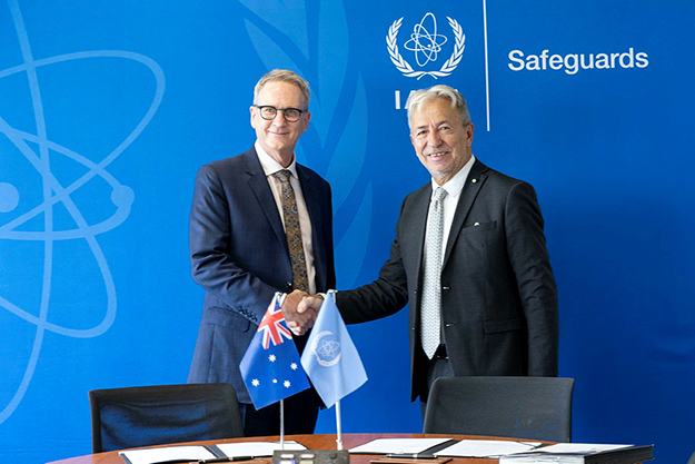 Two men shaking hands and smiling at the camera.
