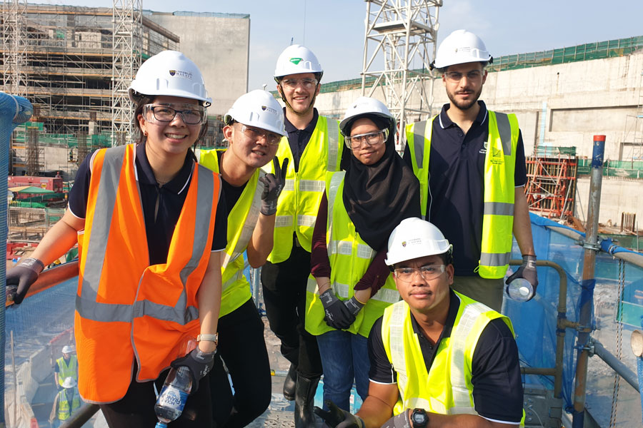 Group photo of construction workers in high viability vest and hard hats on site. 
