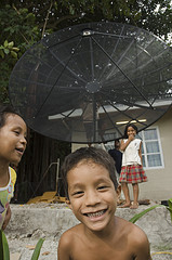 Photo of a child with a satellite dish behind him