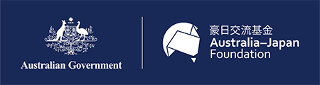 White combined logo on a dark blue background showing the Australian Government crest on the left and the Australia–Japan Foundation logo on the right, separated by a vertical line. The Australia–Japan Foundation logo includes a stylized geometric map shape with bilingual text reading ‘豪日交流基金 Australia–Japan Foundation’.