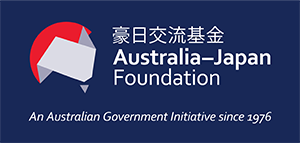 Australia–Japan Foundation logo on a dark blue background, featuring a stylized geometric map shape in red, white, and blue beside bilingual text reading ‘豪日交流基金 Australia–Japan Foundation’. Tagline below says ‘An Australian Government Initiative since 1976’