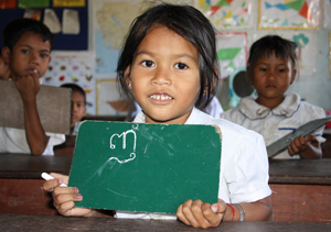 Young female school student holding a small chalk board and smiling