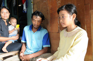 Photo of Anis sitting next to her father and mother, who is holding her baby brother
