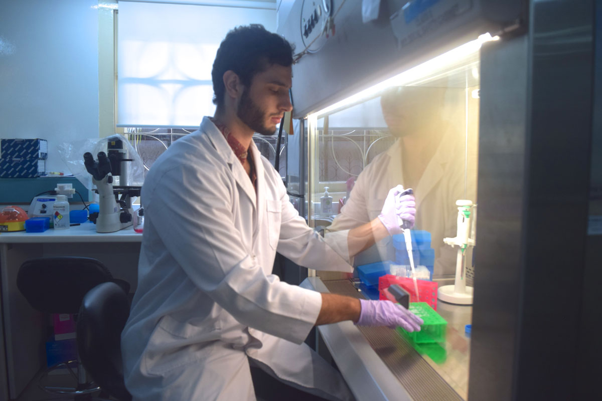 Image of Anton performing laboratory work in a white coat. 