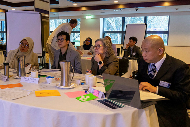 Four attendees of the IAEA Masterclass deep in thought at a round table activity.