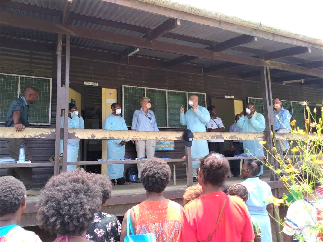 PNG and Australian medical specialists stand on a balcony wearing personal protective equipment, to demonstrate to the audience how the equipment is used.