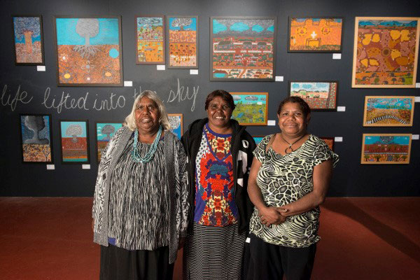 Photo of Mima Smart, Sharon Bryant and Missy Windlass in front of a gallery of Australian indigenous artwork. 