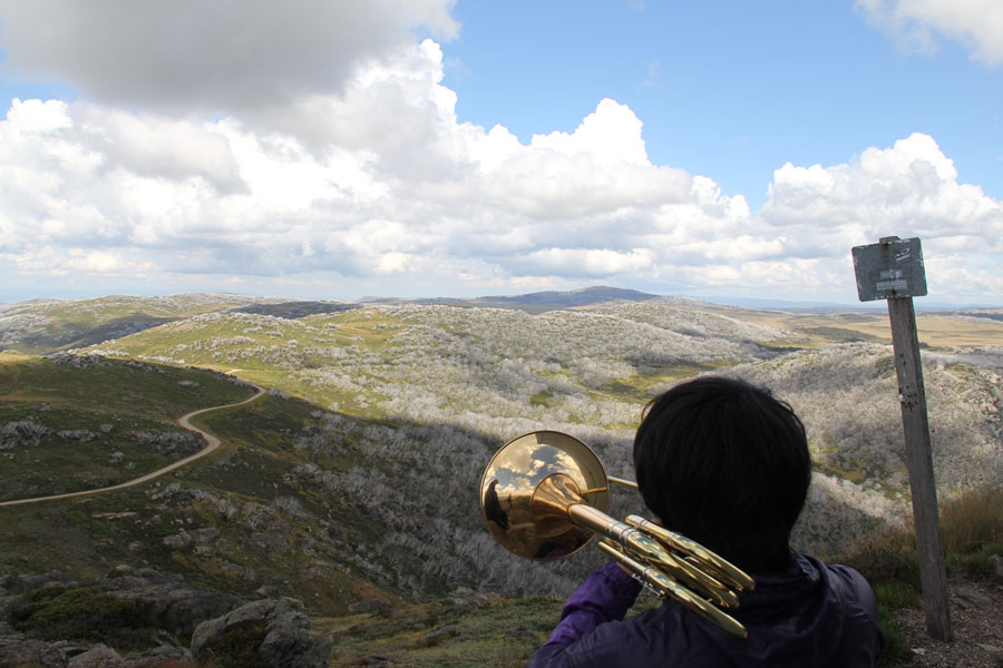 Photo of a person playing an instrument over a valley. 