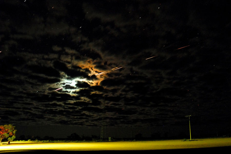 Photo of Hayabusa spacecraft flying across the clouds as it re-enters Earth's atmosphere over the Woomera Test Range in Australia at night-time. 