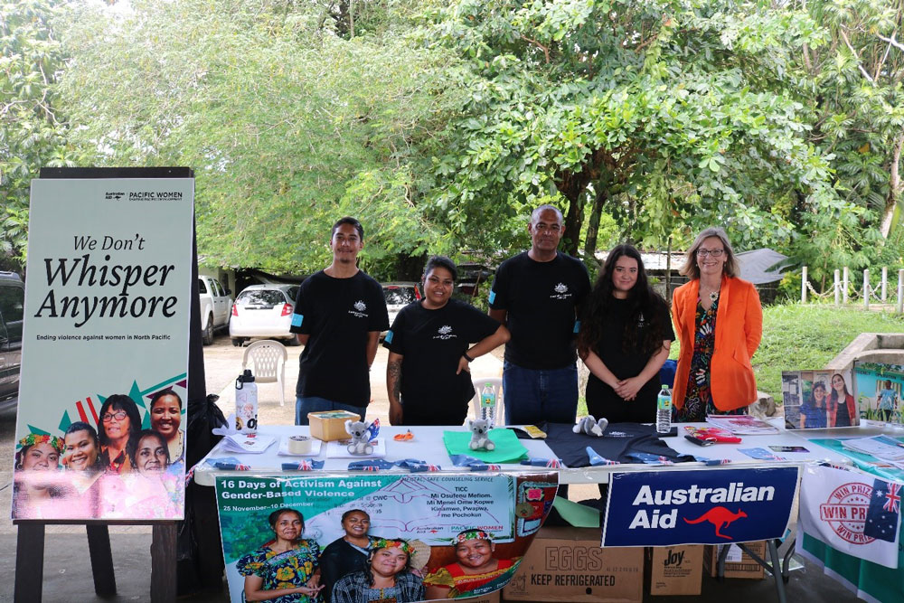 Group photo of Australian Embassy staff in Micronesia with a stall for activism against Gender Based Violence.