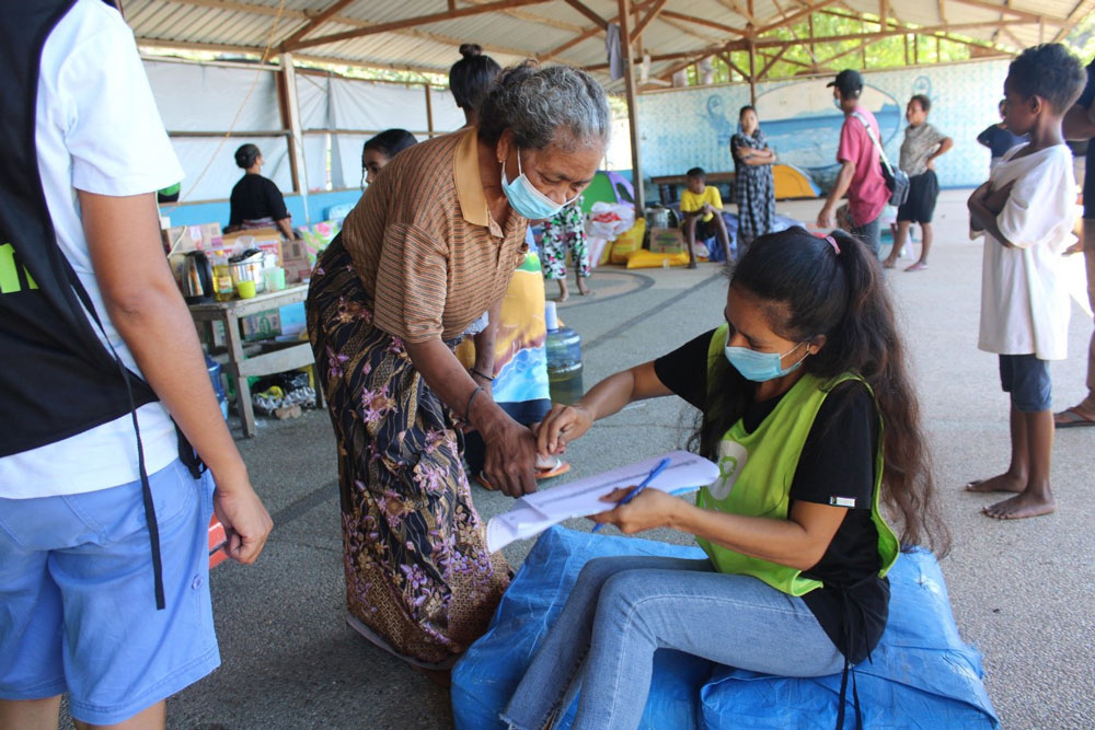 Photo of Oxfam staff member taking details of woman. 