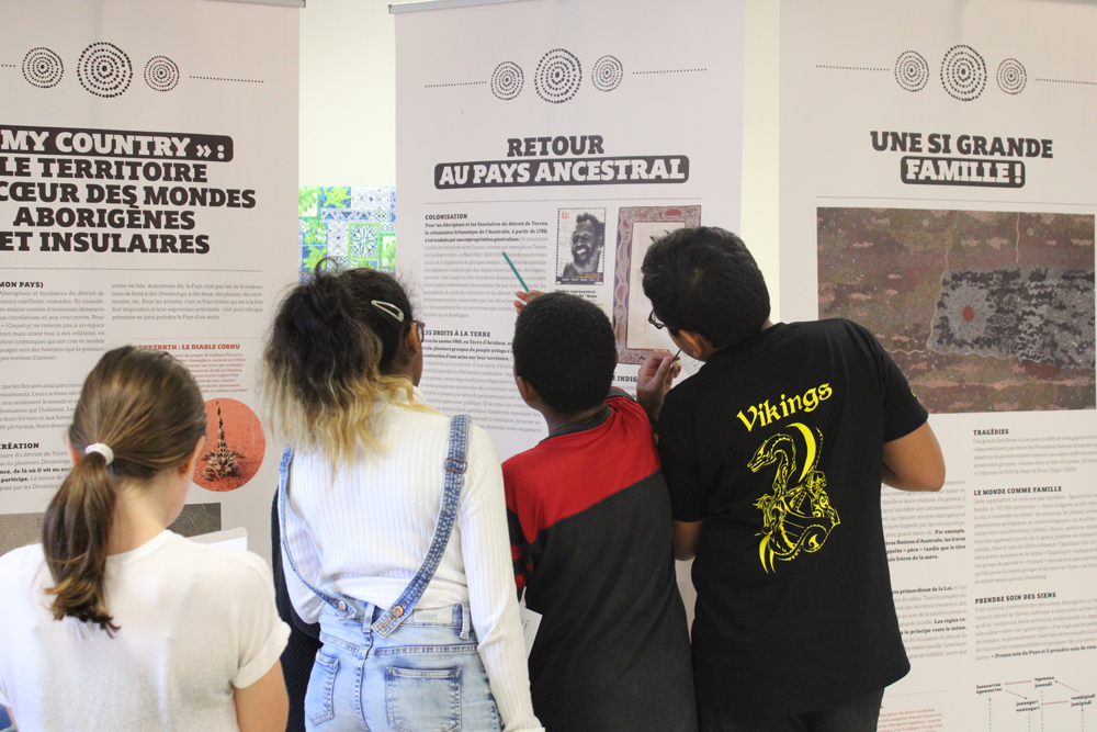 Photo of students in New Caledonia observing an Aboriginal and Islander peoples of Australia art exhibition.