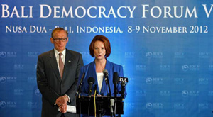 Julia Gillard speaking on stage at the forum, with Bob Carr standing to her right
