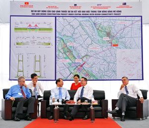 Men seated and smiling in front of large map showing where new bridge will be located