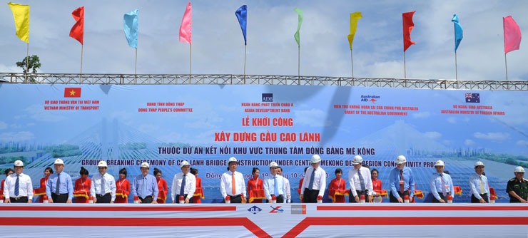 Men standing behind a long table with large red buttons in front of them