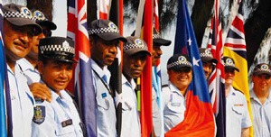Police from across the Pacific holding their countries' flags and smiling at the camera