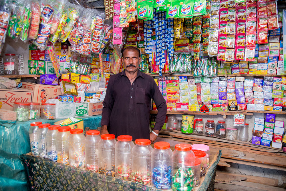 Photo of Anwar selling multiple products in an open street side store. 