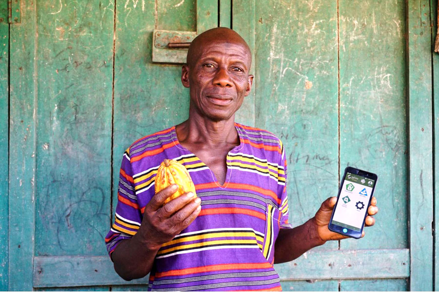 Photo of a person holding a piece of fruit and a phone with the AgUnity app open.