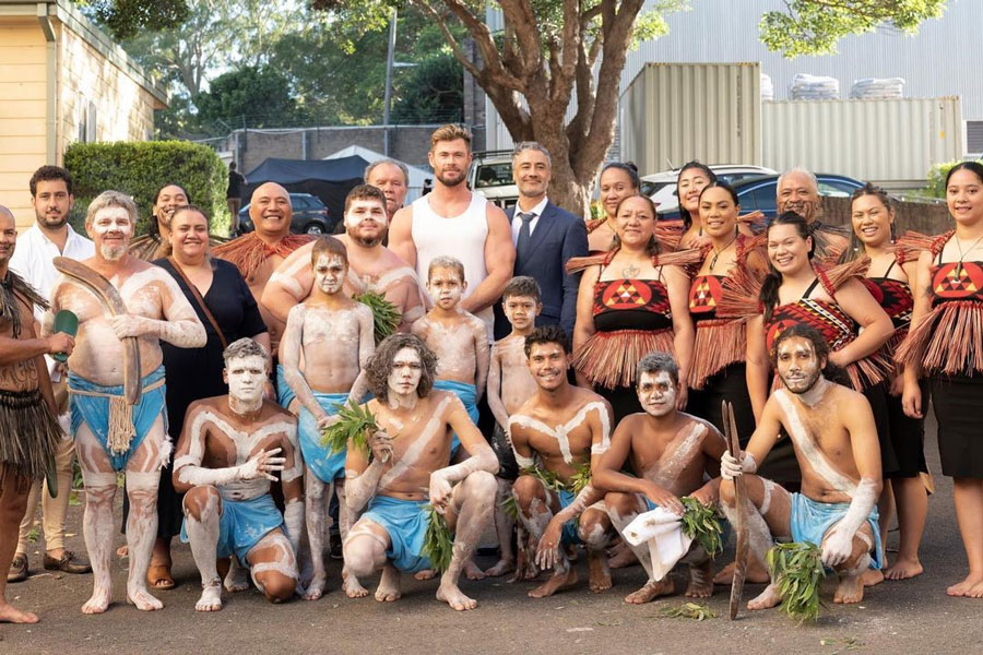 Group photo of Movie director Taika Waititi and Actor Chris Hemsworth with Indigenous peoples dressed in cultural attire. 