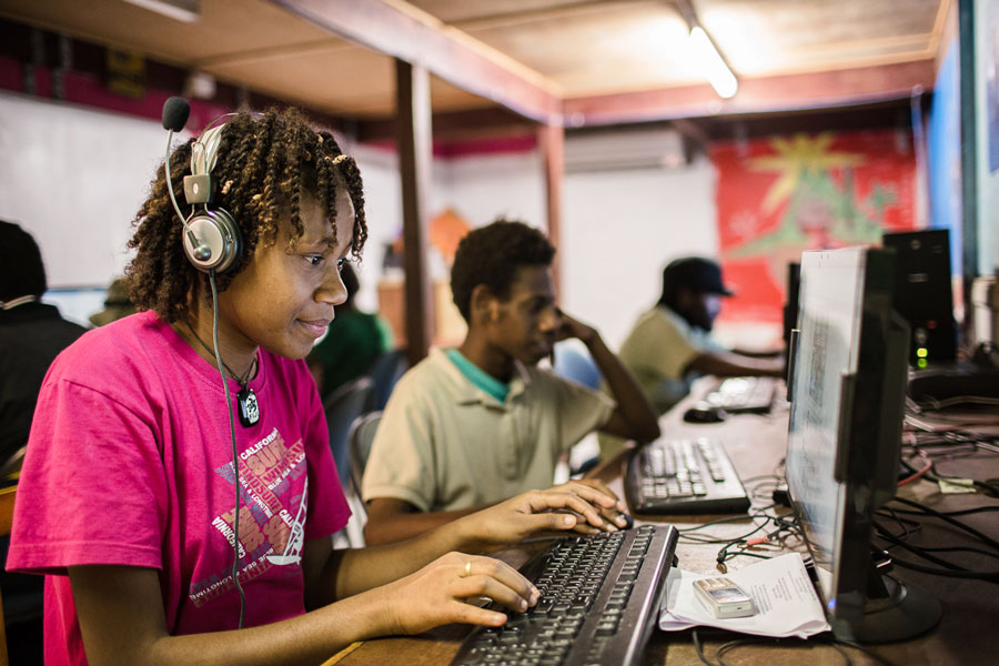 Photo of Yolanda in Grade 10 using a computer with other students using computers in the background. 