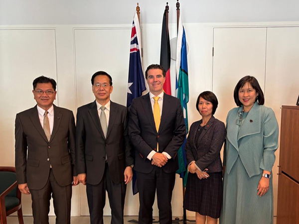Four Mekong subregion officials standing in an office engagement with an Australian Government official, in front of a backdrop of the Australian National, Australian Aboriginal and Torres Strait Islander flags.