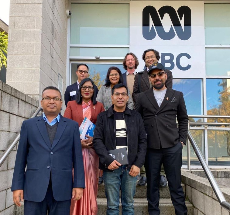 A group of officials standing in front of the Australian Broadcasting Corporation building
