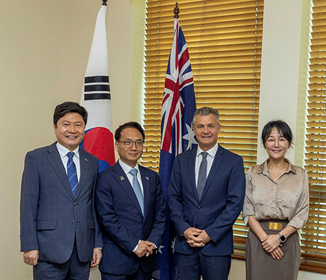 Three South Korean parliamentarians and one Australian minister stand side by side in formal attire, smiling towards the camera. They are inside Parliament House and are standing in front of the Australian flag and the Republic of Korea flag. 