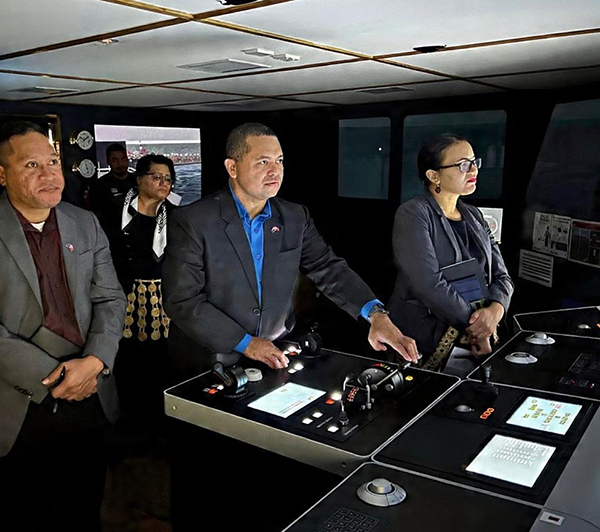 A group of people gather in a simulation room of a ship’s bridge at the Australian Maritime College. A delegate is operating the controls.