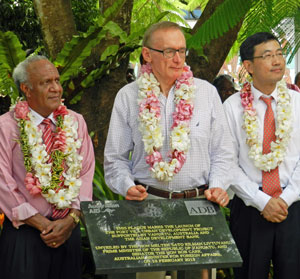 Mr Carr stands between two other men, behind plaque