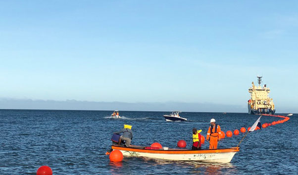 Photo of boats inspecting floating devices in the ocean attached to the Coral Sea Cable.