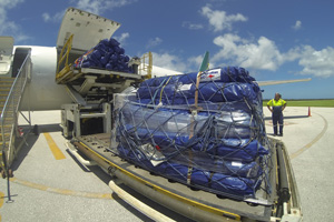 Large aeroplane on tarmac with contents being unloaded.