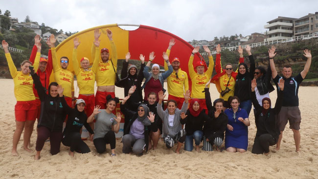 Photo of delegates with surfer life savers. Everyone putting their hands up.