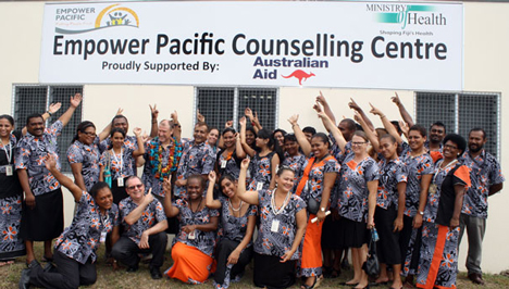 A group of people under a sign for the Empower Pacific Counselling Centre