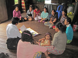 A small group of children and adults gathered in a circle learning about safe migration.