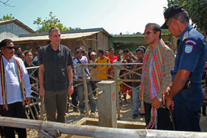 Large group of people, including officials, standing around a tap