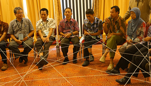 People sitting holding strings between each other