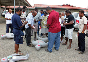 Men and women gathered around a medical mannequin on the ground