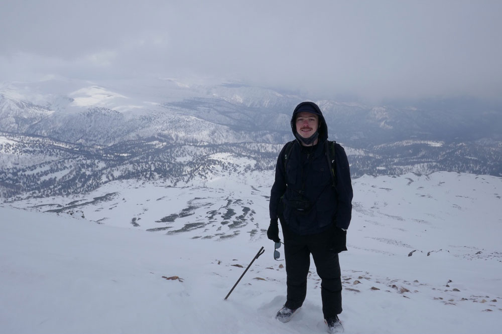 Photo of Ethan on top of a snowy mountain. 