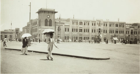 Photo of people walking around with umbrellas in a town.
