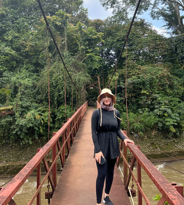 Fatima standing on a bridge over a river