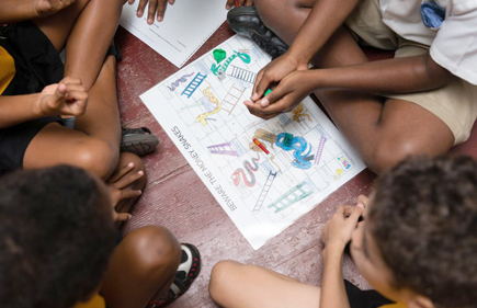 Children sitting around a game on a piece of paper
