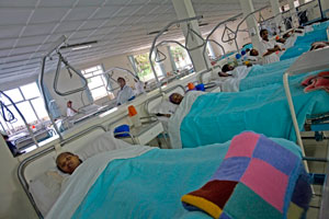 Photo of rows of hospital beds with women patients tucked in with blue blankets