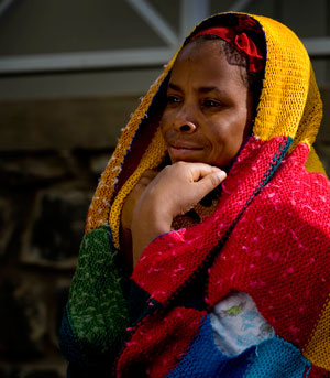 Photo of a woman wrapped in colourful blanket staring