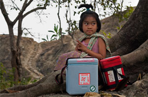 A child sits with medical boxes containing vaccines in Bangladesh