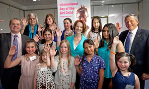 Prime Minister Julia Gillard surrounded by smiling men, women and girls with hands raised in support of girls' education.